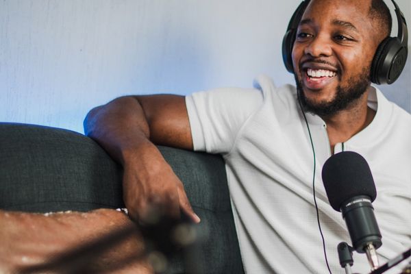 podcaster with headphones smiling over microphone