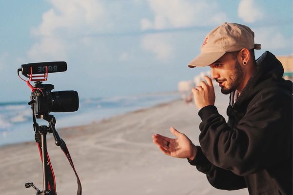 vlogger recording video on the beach starring into the camera