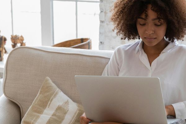 woman of color working on laptop on sofa